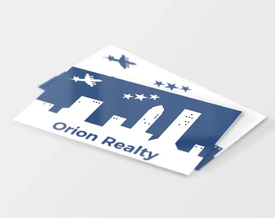 An Orion Realty business card with the skyline mark, shown at an angle.
